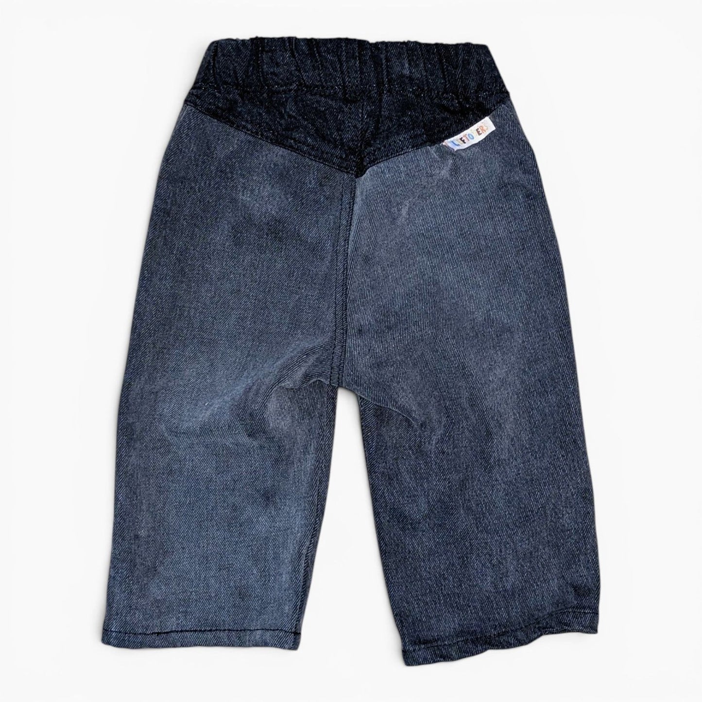 A pair of Leftovers Club Stevie Straight black denim jeans for kids, featuring an elastic waistband, front pockets, and contr