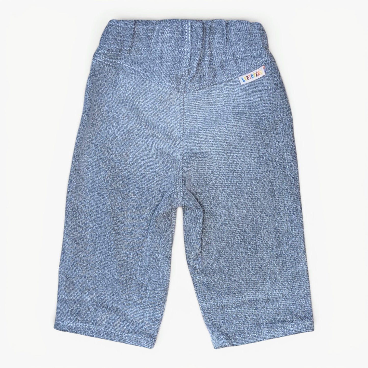 Light grey denim pants for toddlers, shown from the back on a plain off-white background. The back features an elastic waistband and a small woven brand tag on the upper right side.
