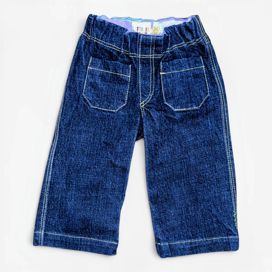 A pair of dark blue denim pants with white contrast stitching, featuring two large patch pockets on the back, laid flat against a white background.