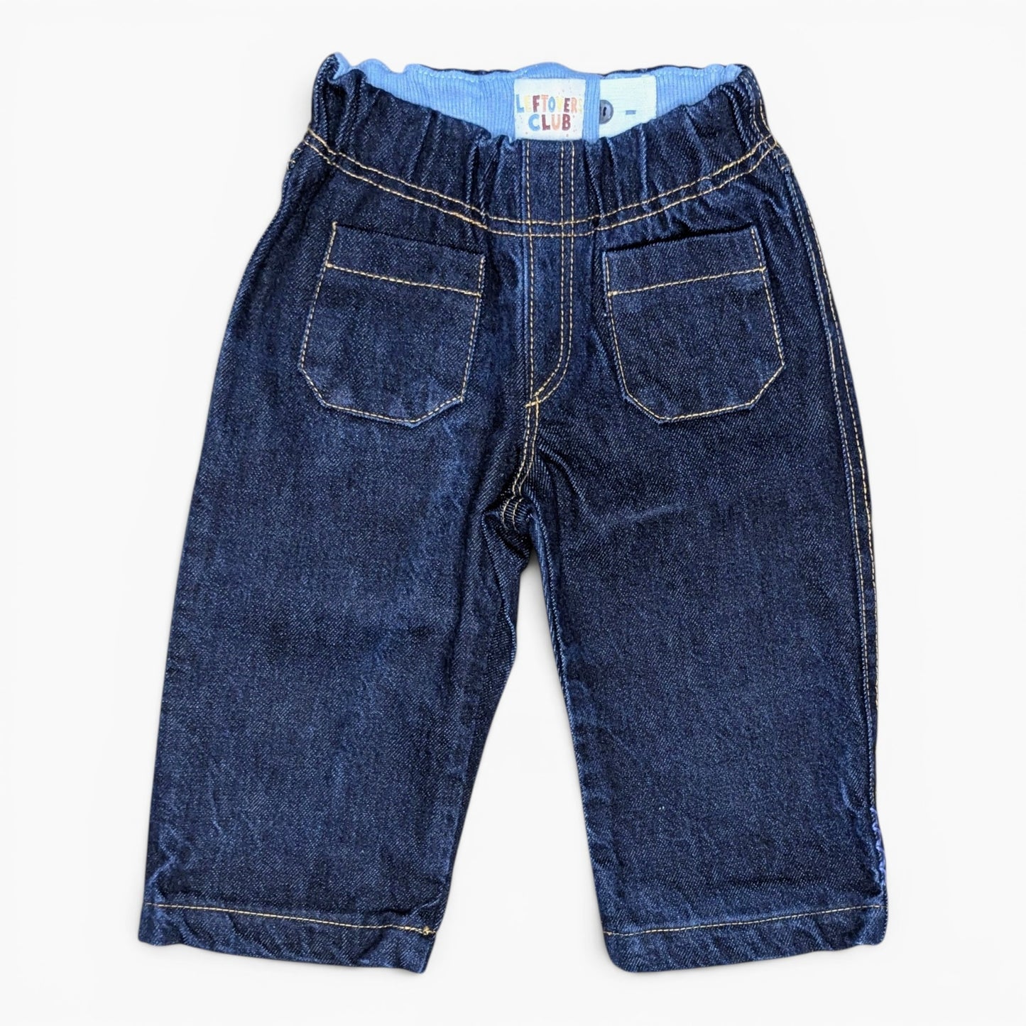 A pair of dark blue denim shorts for toddlers, featuring an elastic waistband, two back patch pockets, and contrast light-colored stitching, shown flat on a white background.