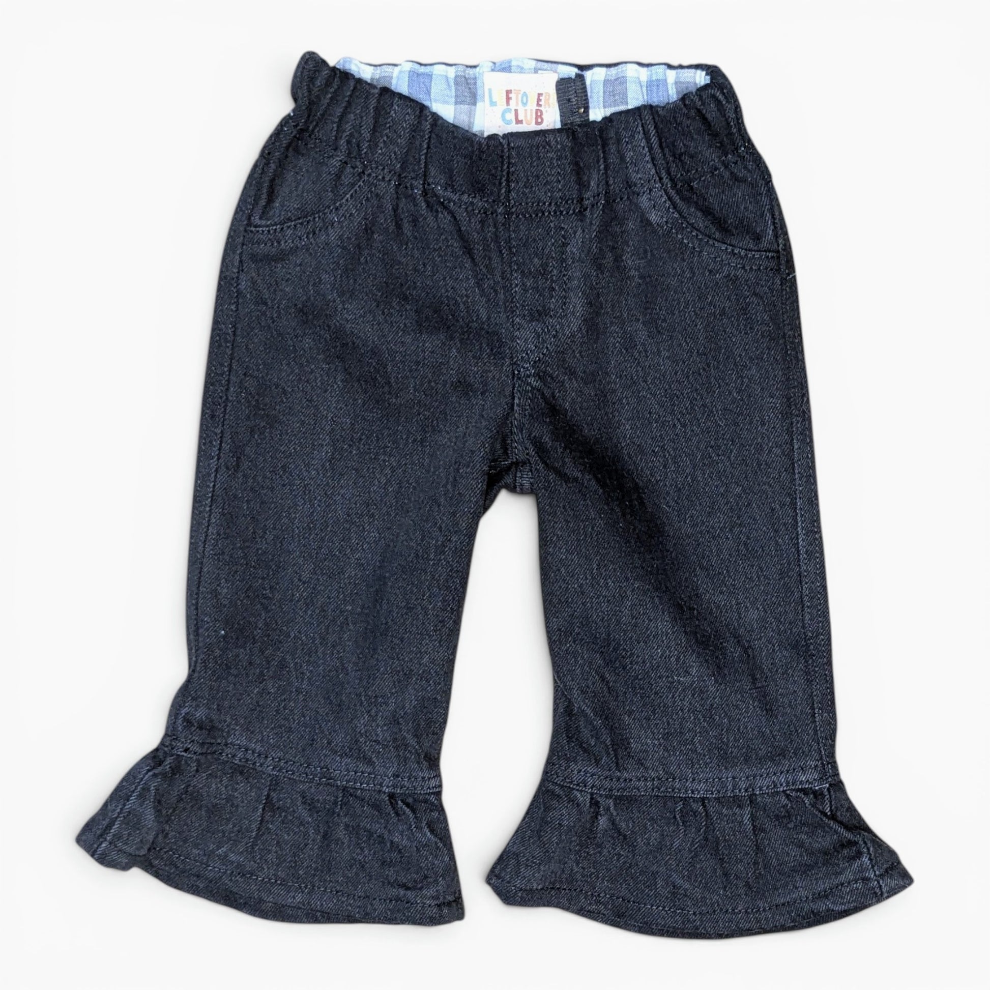 A pair of dark blue denim cropped pants with a ruffled hem and a light blue and white striped inner waistband, shown flat on a white background.