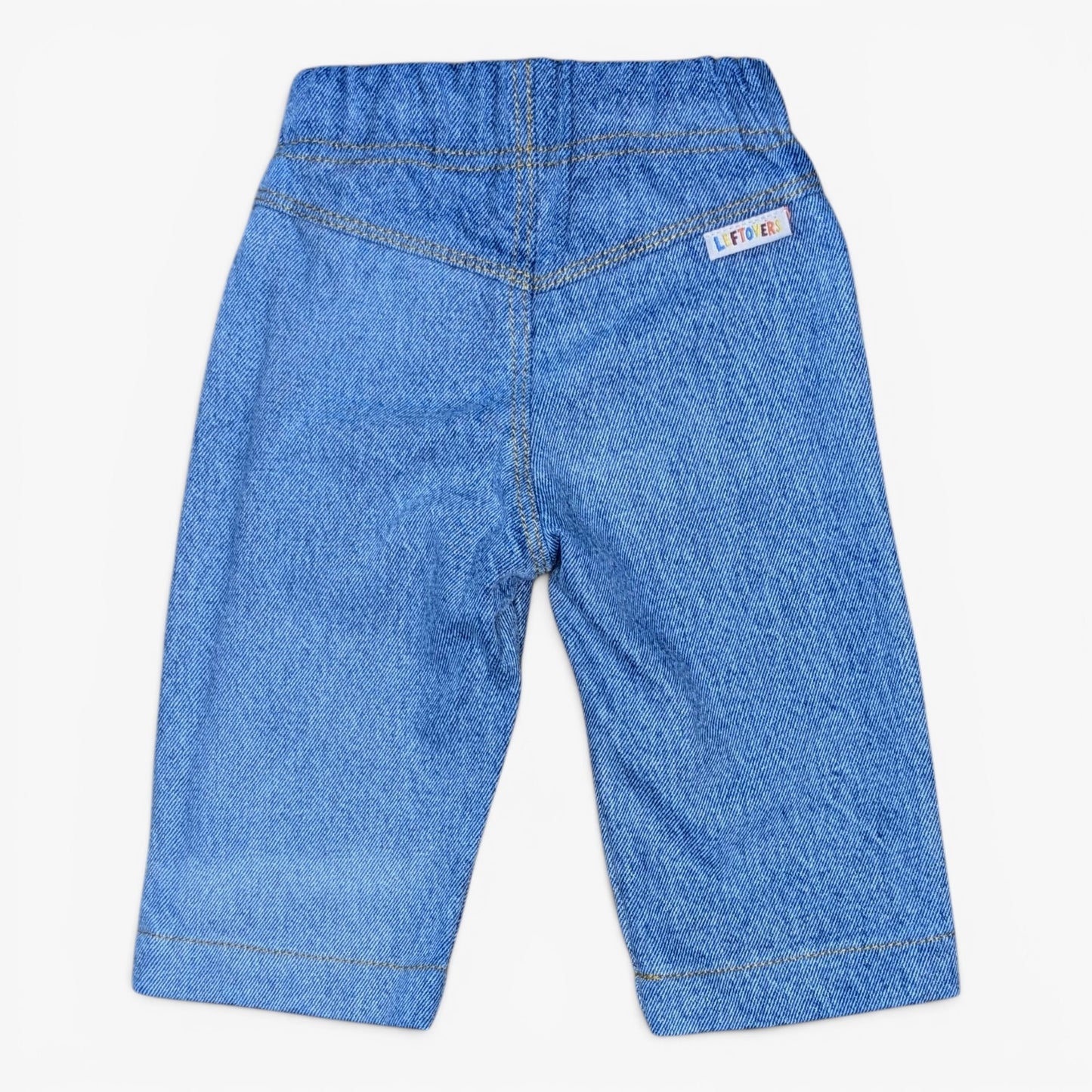 Blue denim pants shown from the back, featuring a wide elastic waistband, contrast stitching, and a small white brand tag on the upper right side.