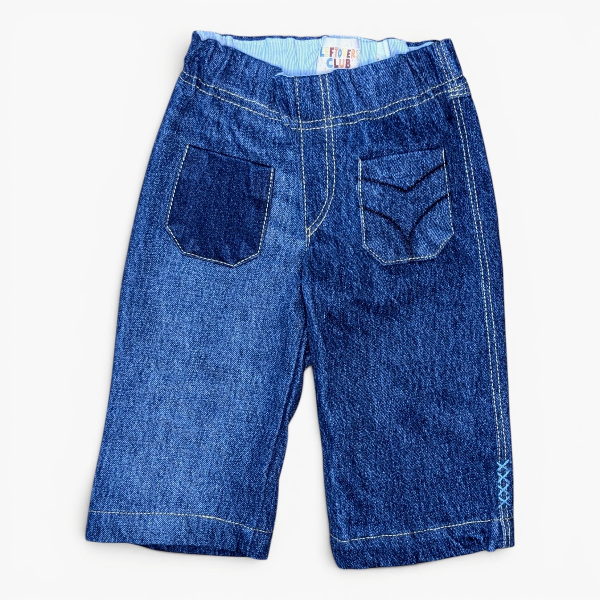 A pair of blue denim pants with a wide elastic waistband, featuring two back patch pockets with decorative stitching, photographed flat on a white background.
