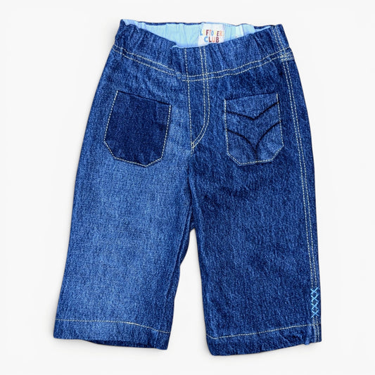 A pair of blue denim pants with a wide elastic waistband, featuring two back patch pockets with decorative stitching, photographed flat on a white background.