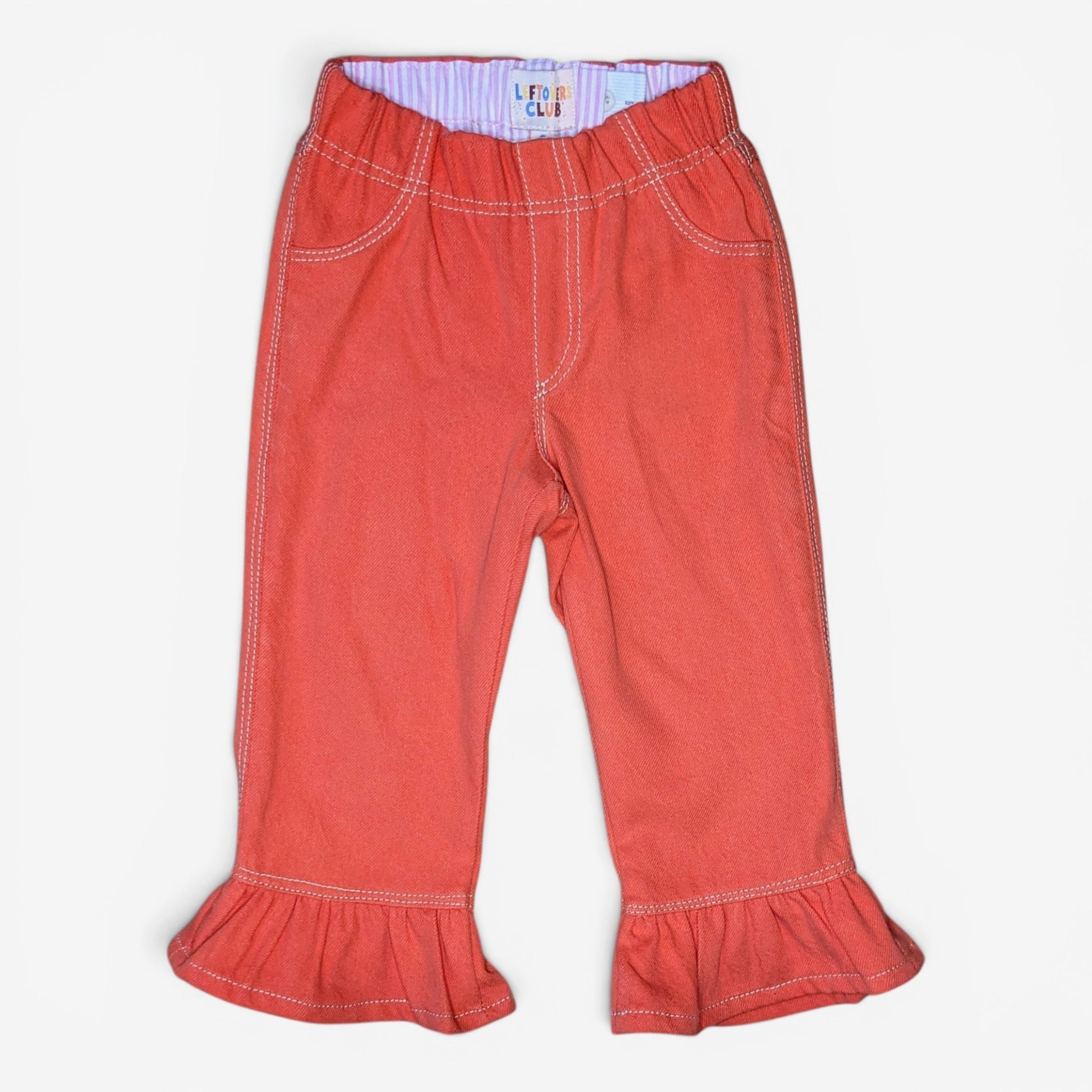 A pair of toddler's coral red denim pants with ruffled cuffs, front pockets, and contrast stitching, shown flat on a white background.