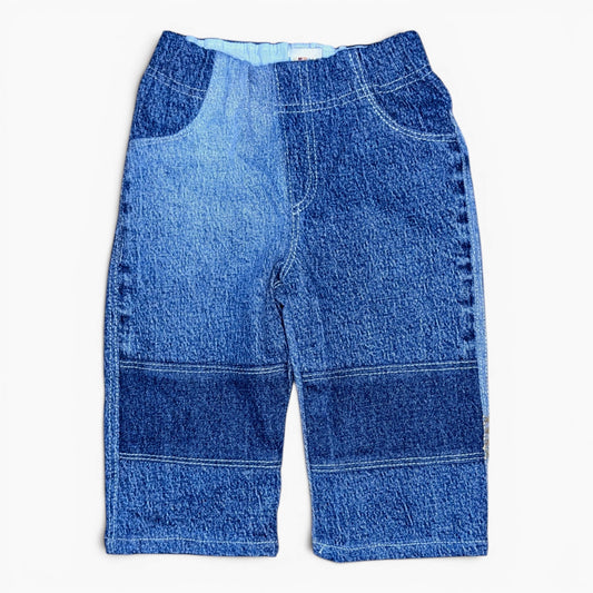 A pair of blue denim pants with a patchwork design of different blue washes, laid flat against a white background.