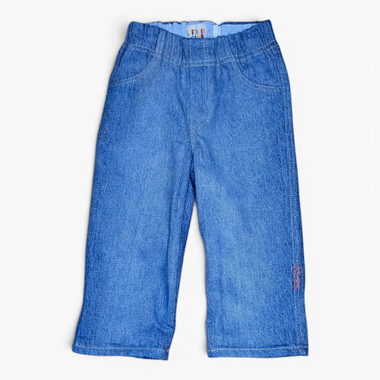 A pair of blue denim pants with an elastic waistband, laid flat against a light off-white background.