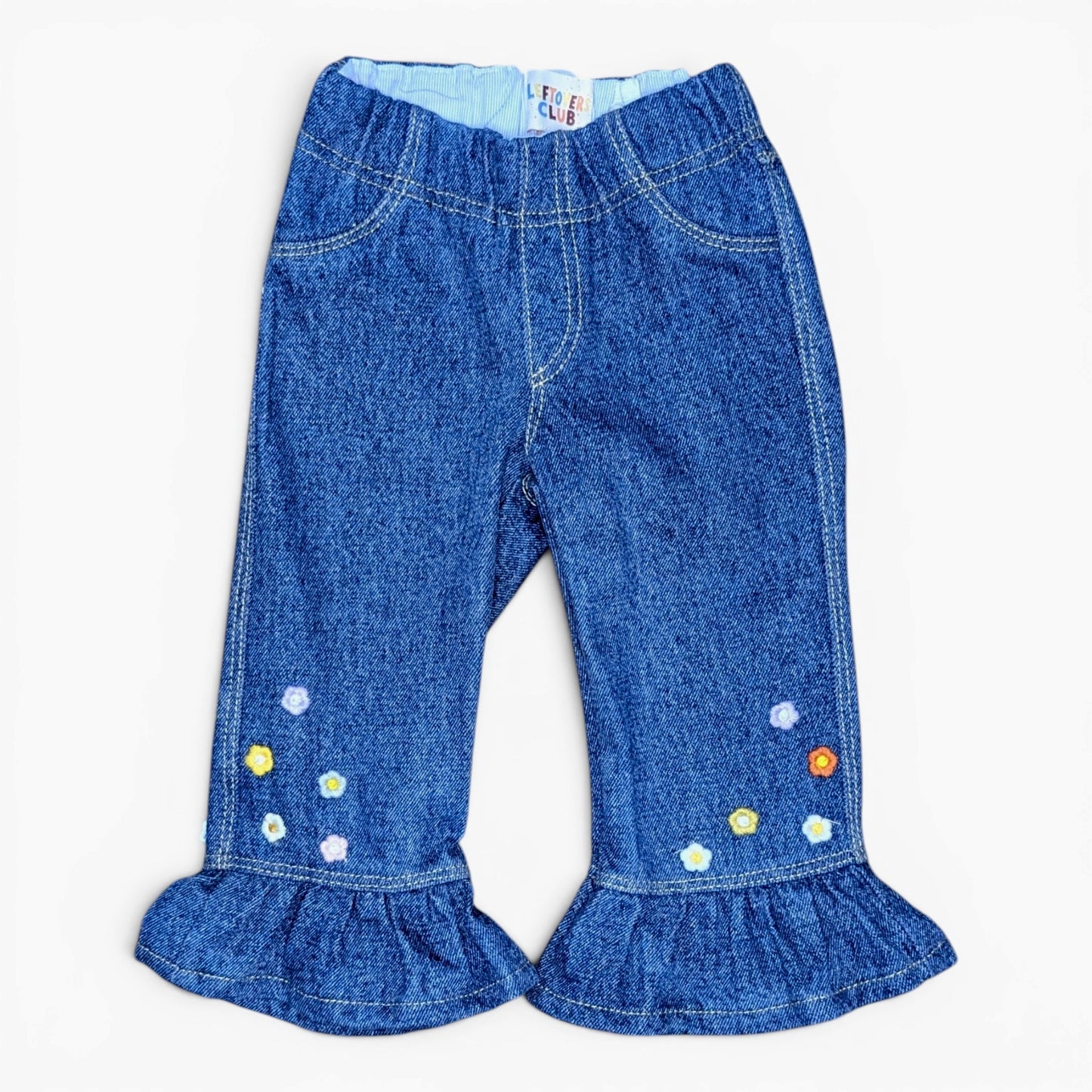 A pair of toddler blue denim flare pants with ruffled hems and small embroidered flowers on the lower legs, shown flat on a white background.