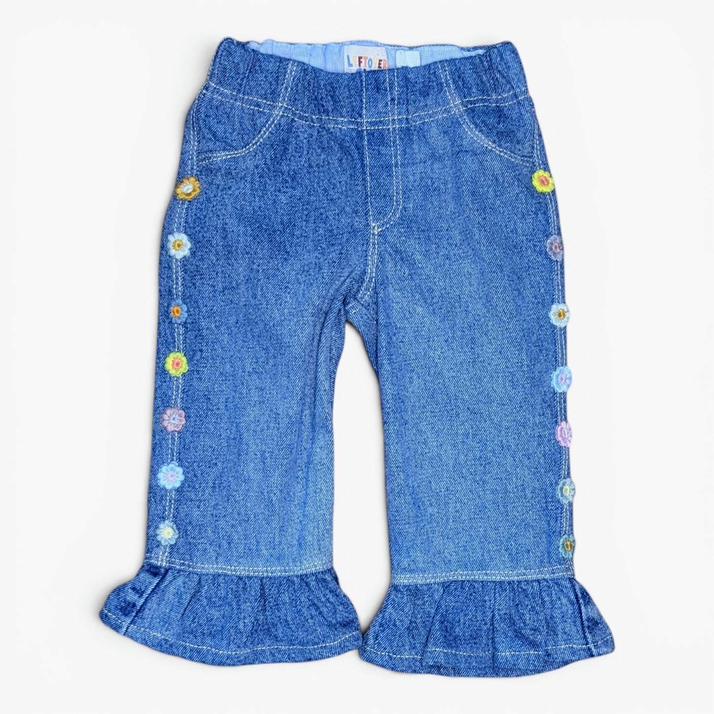 Blue denim flare pants for toddlers, featuring colorful embroidered flowers down the sides and ruffled hems, shown flat on a white background.