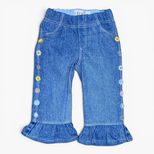 Blue denim flare pants for toddlers, featuring colorful embroidered flowers down the sides and ruffled hems, shown flat on a white background.