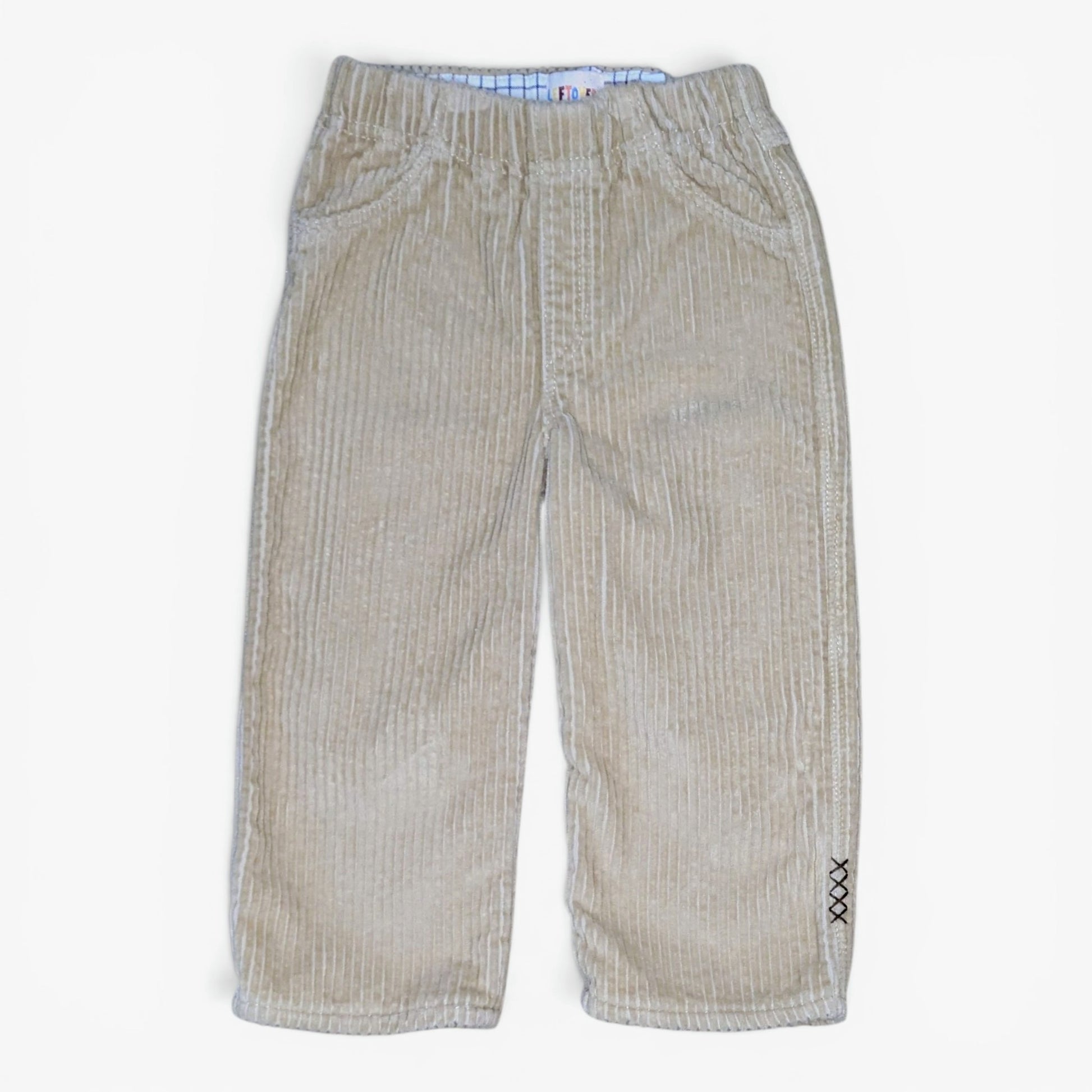 A pair of beige corduroy pants for toddlers, featuring an elastic waistband, front pockets, and a small black embroidered 'XX' detail on the lower left leg, shown against a plain white background.