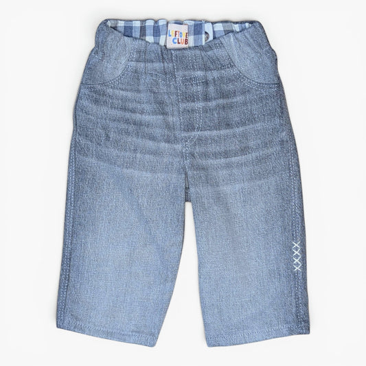 Light grey denim pants for toddlers, featuring a gusseted front pocket design, elastic waistband with a blue and white checkered lining, and white embroidered 'XXX' details on the lower left leg.