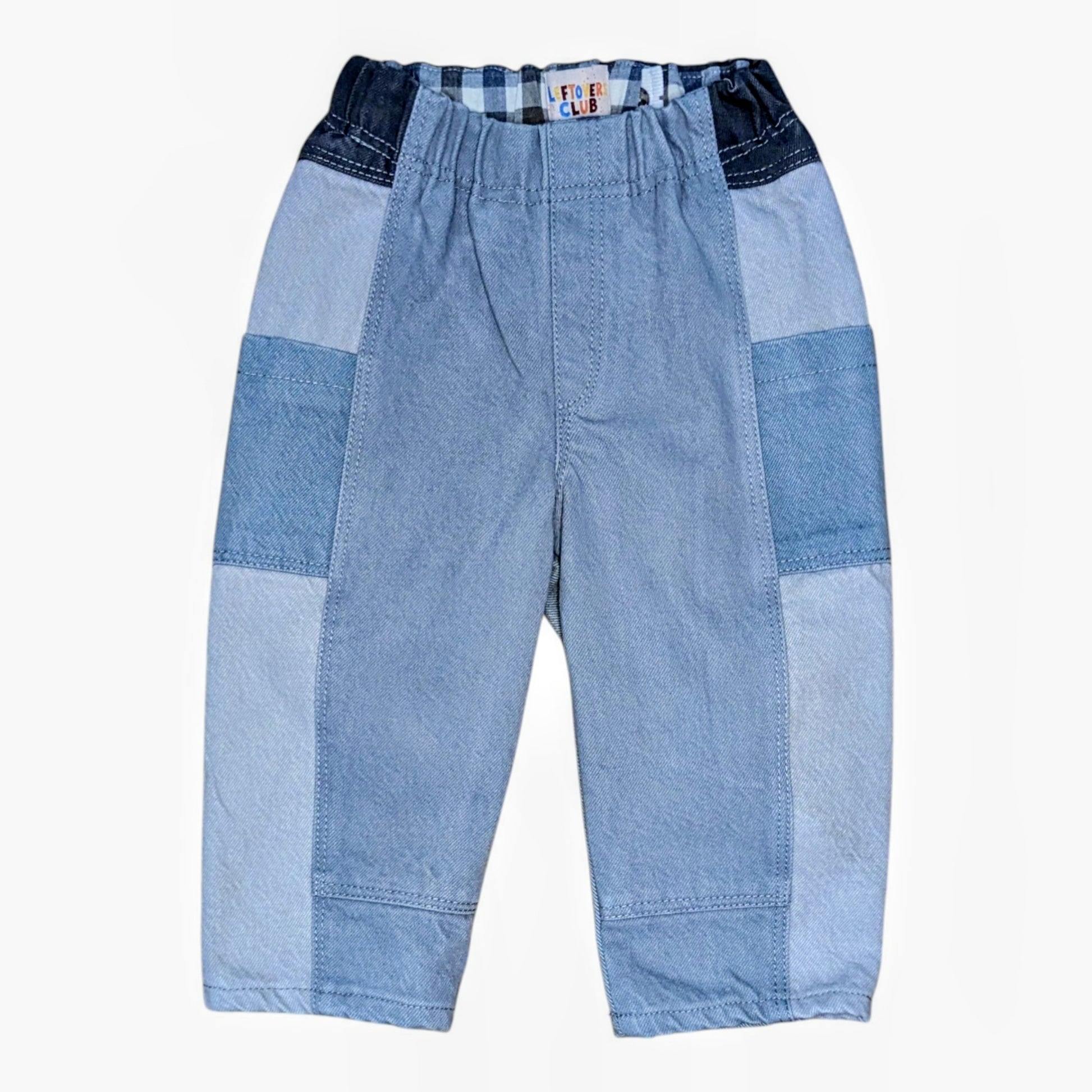 A pair of patchwork denim pants for toddlers, featuring light blue and medium blue denim panels with a dark blue plaid waistband, shown against a plain white background.