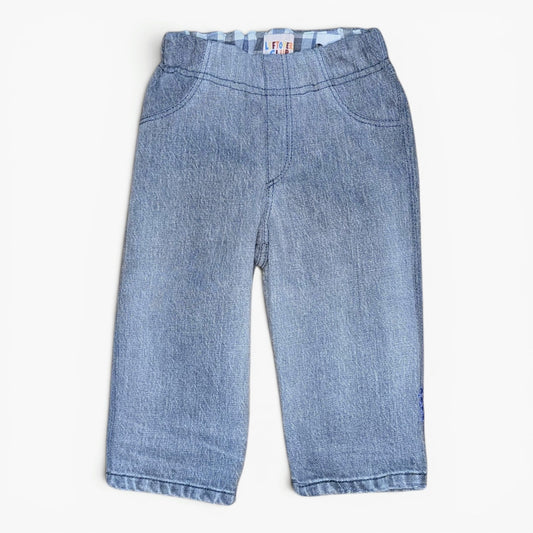 Light blue denim pants for toddlers, featuring a wide elastic waistband with a striped lining and front patch pockets, laid flat on a white background.