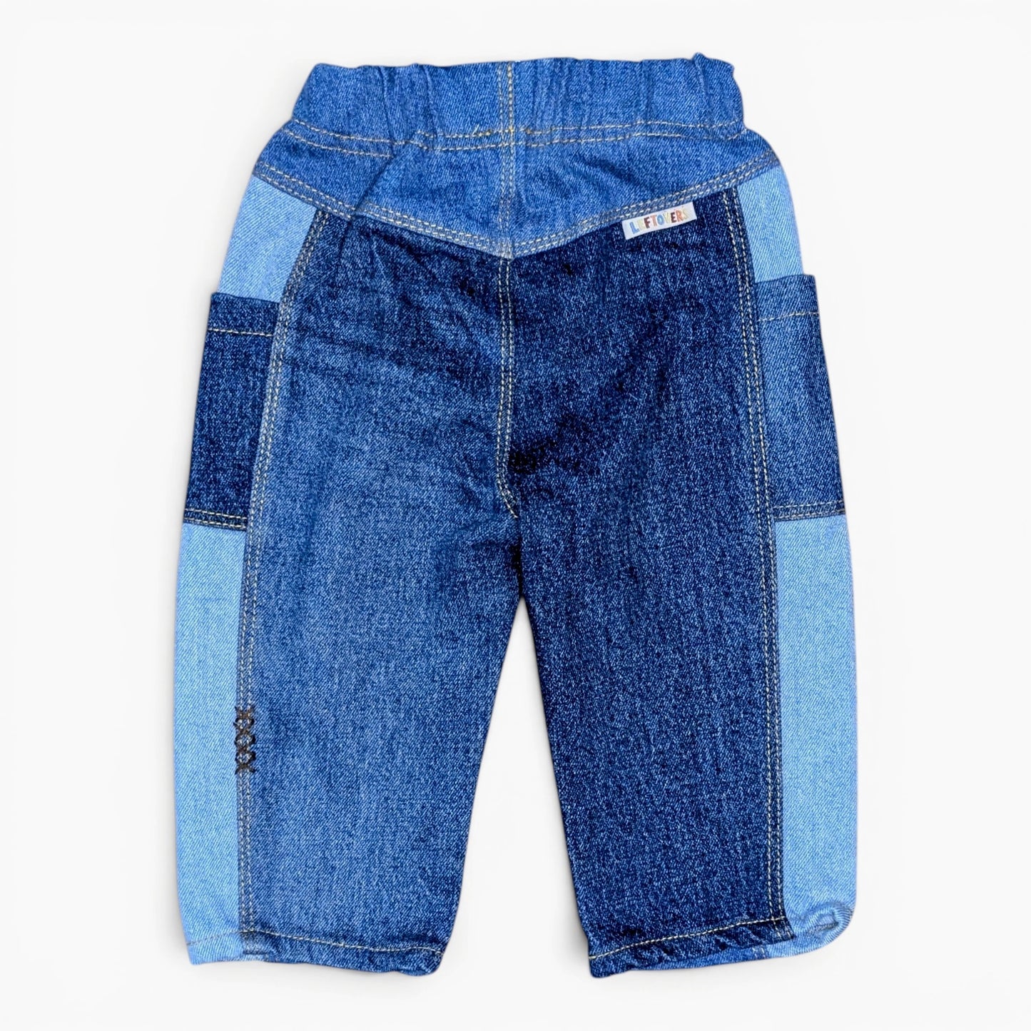 A pair of children's denim pants featuring a patchwork design with dark blue, medium blue, and light blue denim panels, shown flat against a white background.