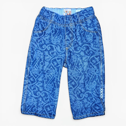 Blue patterned denim pants for toddlers with a graffiti design, laid flat against a white background.