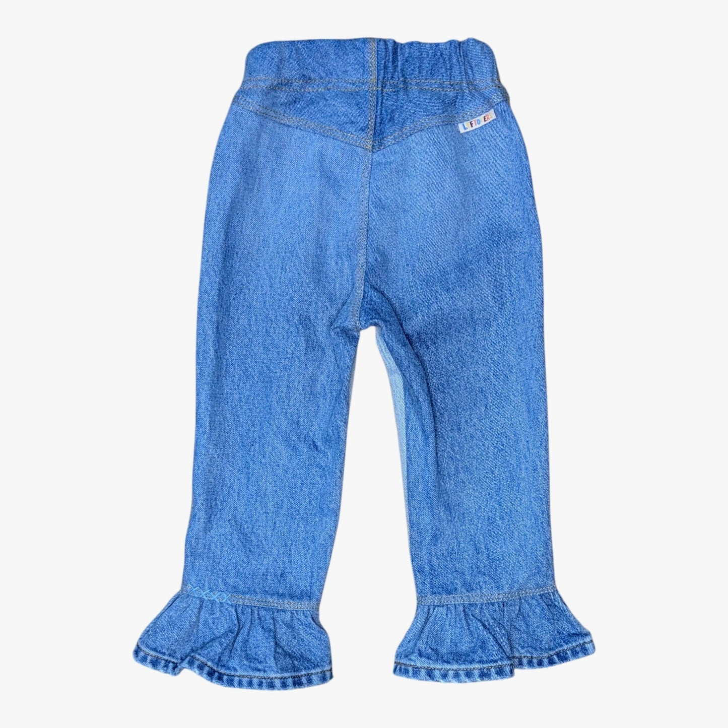 Blue denim pants for toddlers, featuring an elastic waistband and ruffled hems, shown against a plain white background.
