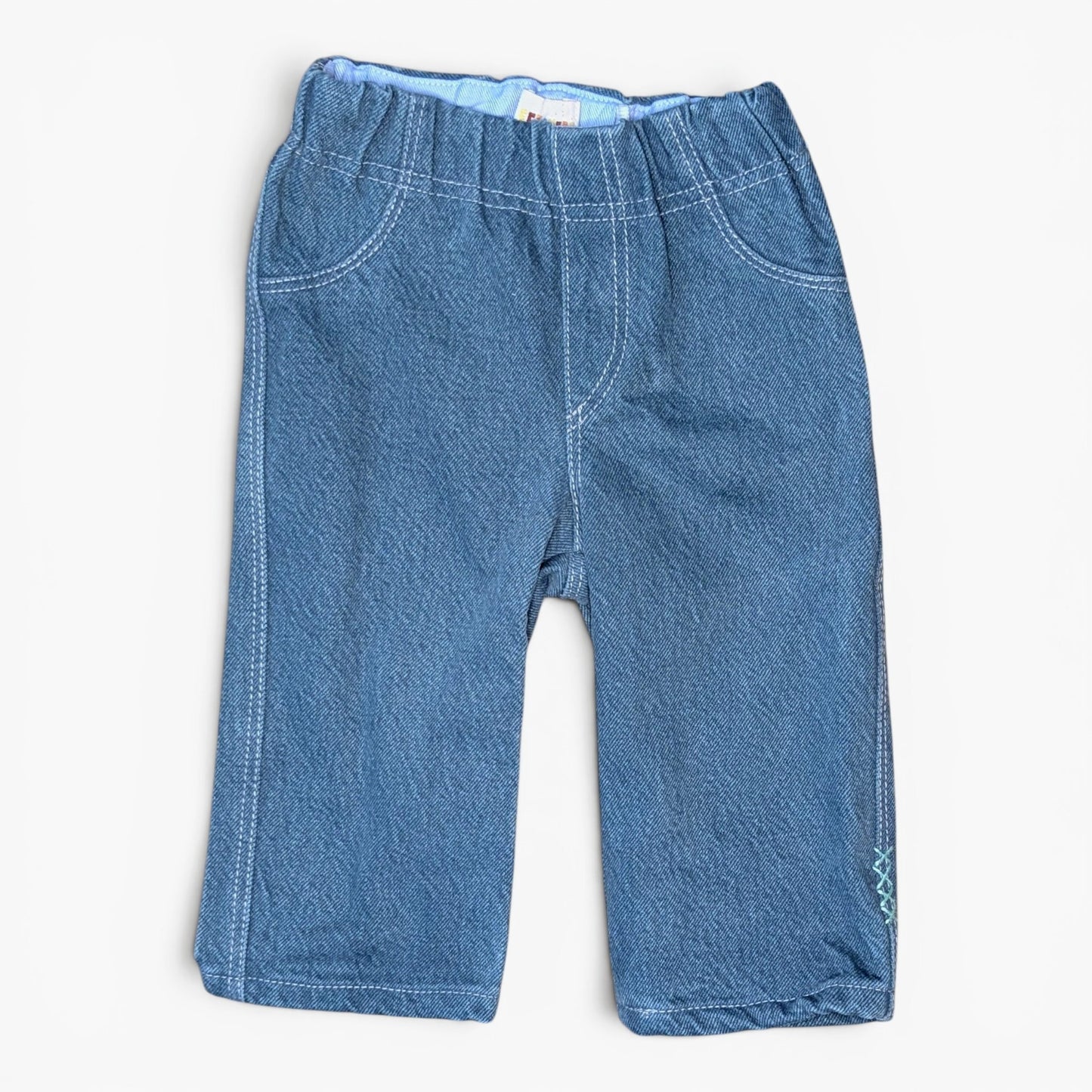 A pair of blue denim jeans for kids, featuring an elastic waistband, front pockets, and contrast stitching, laid flat against a light off-white background.