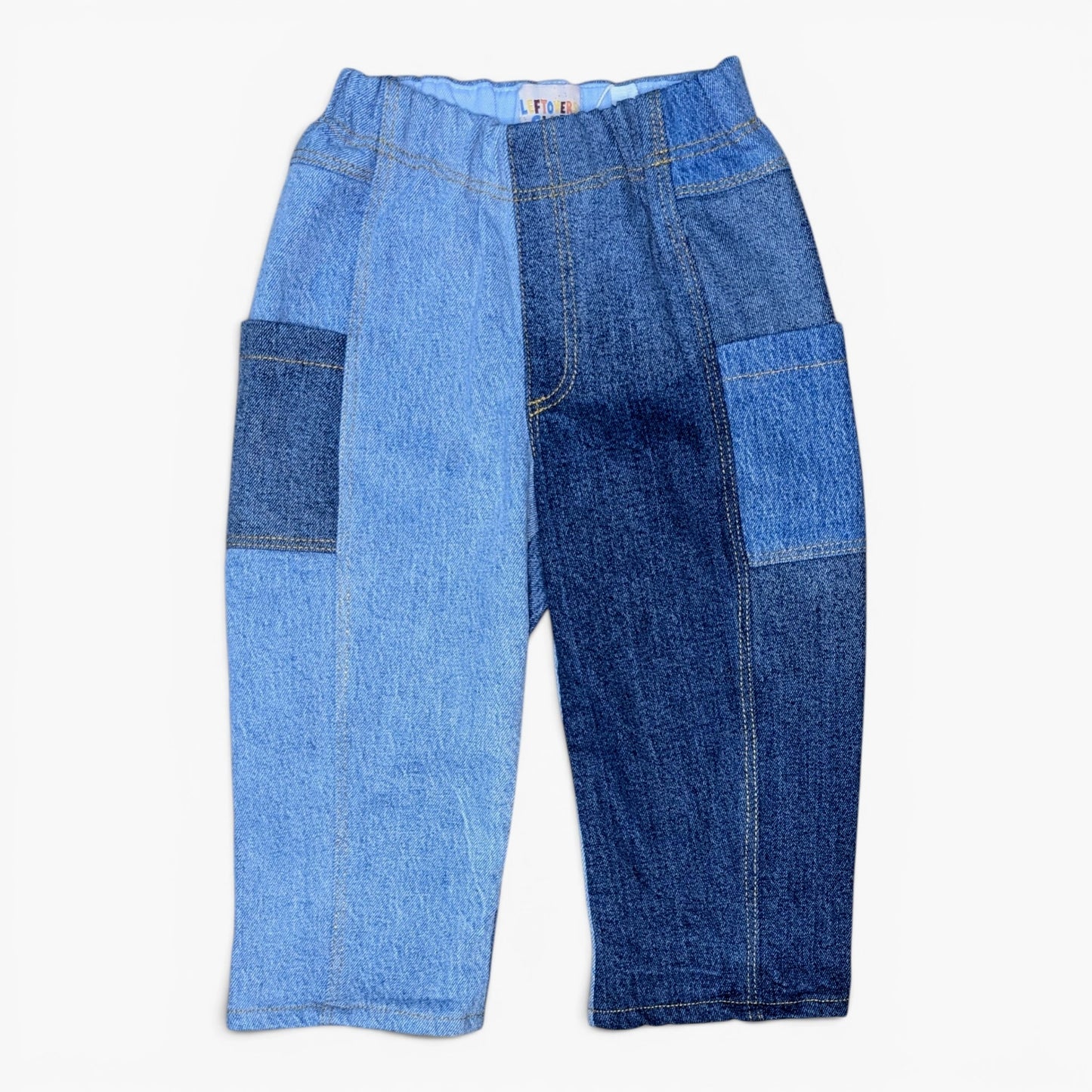 A pair of denim pants with a split-color design, featuring light blue denim on the left leg and dark blue denim on the right leg, with matching patch pockets on the thighs.